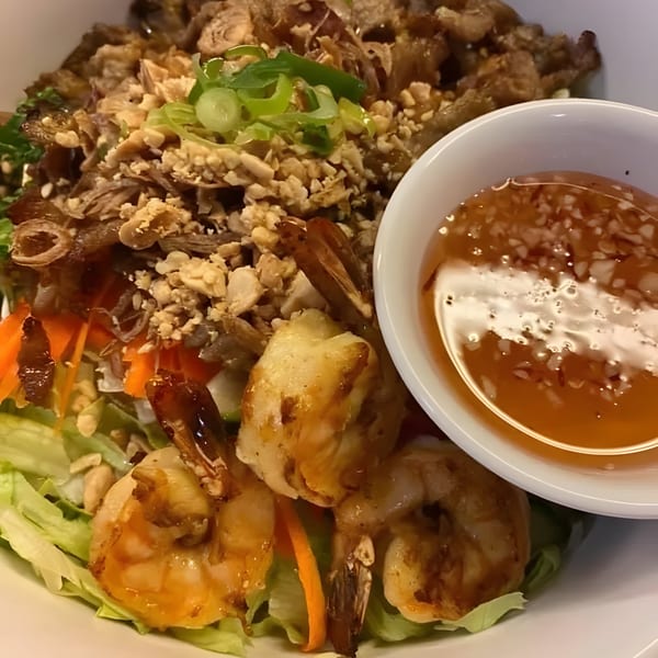 Thai salad with shrimp, shredded chicken, peanuts, green onions, and a side of sauce.