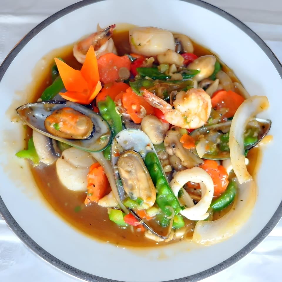 Thai seafood stir-fry with mussels, shrimp, squid, and vegetables in a savory sauce.